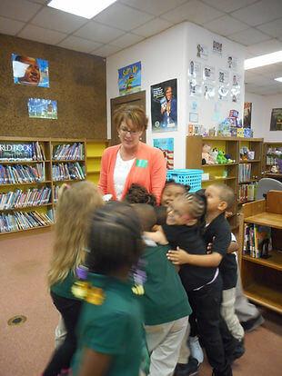 Group of students hugging a presenter in a library